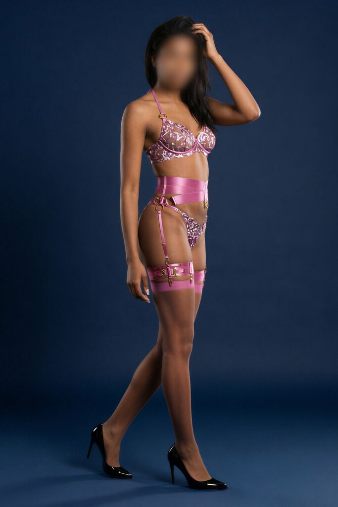 Nederlandse Courtisane Model in lingerie met een paarse en roze kleurstelling, poseert met een hand in het haar en een elegante uitstraling. Amsterdam Den Haag Rotterdam Utrecht Antwerpen